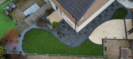 Aerial view of a landscaped garden with curved patio and lawn